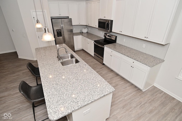 kitchen featuring stainless steel appliances, light wood-type flooring, a sink, and a breakfast bar