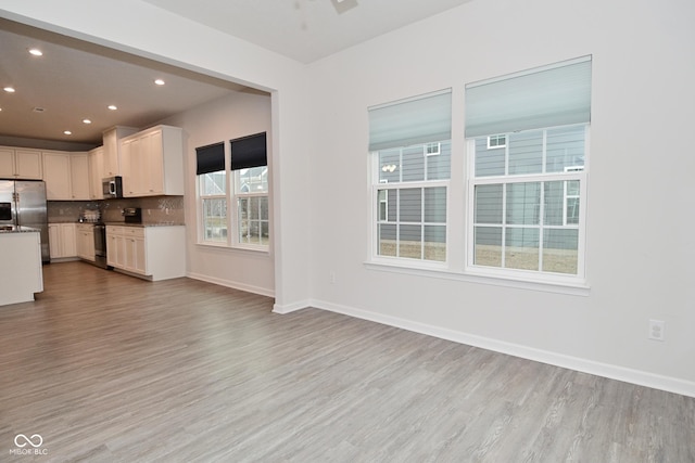 interior space with tasteful backsplash, baseboards, stainless steel appliances, light wood-type flooring, and recessed lighting