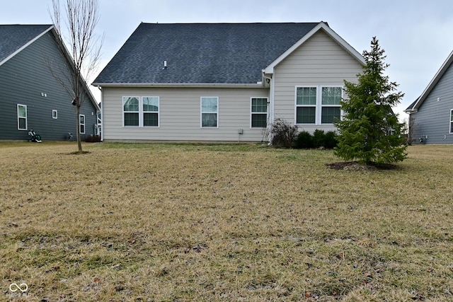 rear view of property with a lawn and roof with shingles