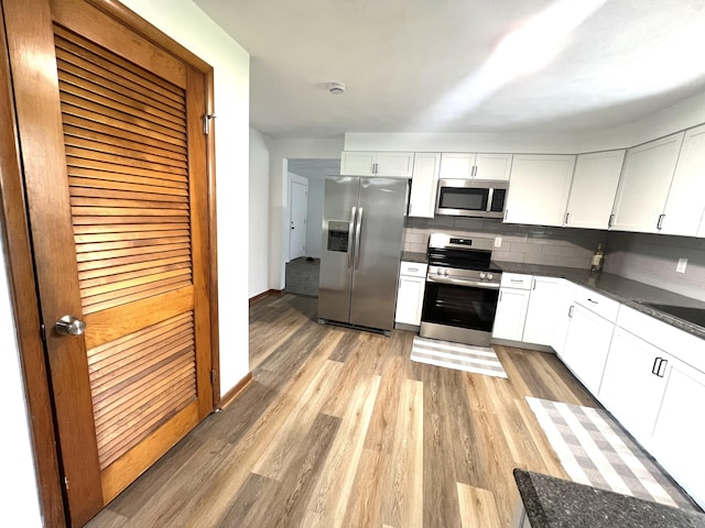 662 S County Road 150 W, Greensburg, IN 47240 - kitchen with appliances with stainless steel finishes, dark countertops, light wood-type flooring, decorative backsplash, and white cabinets