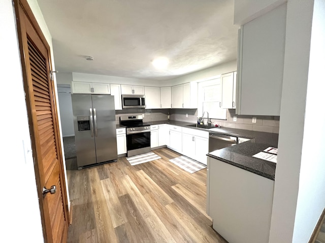 662 S County Road 150 W, Greensburg, IN 47240 - kitchen featuring appliances with stainless steel finishes, tasteful backsplash, light wood finished floors, white cabinetry, and dark stone countertops