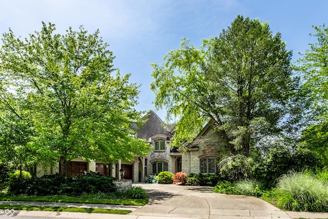 french country home featuring stone siding and concrete driveway