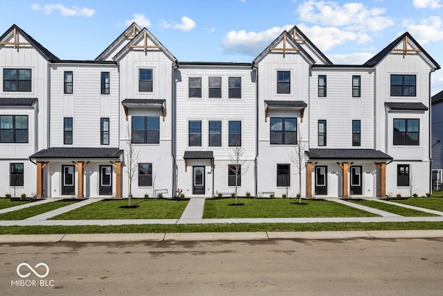 townhome / multi-family property with board and batten siding and a front yard