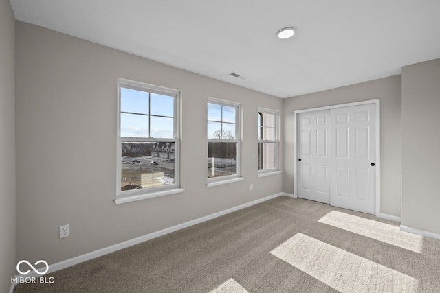 unfurnished bedroom with carpet, a closet, visible vents, and baseboards