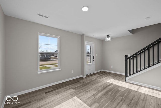 entryway featuring wood finished floors, visible vents, baseboards, and stairs