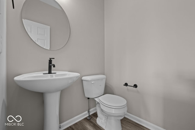 bathroom featuring toilet, baseboards, and wood finished floors