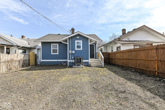 rear view of property with a chimney, a fenced backyard, and a shingled roof