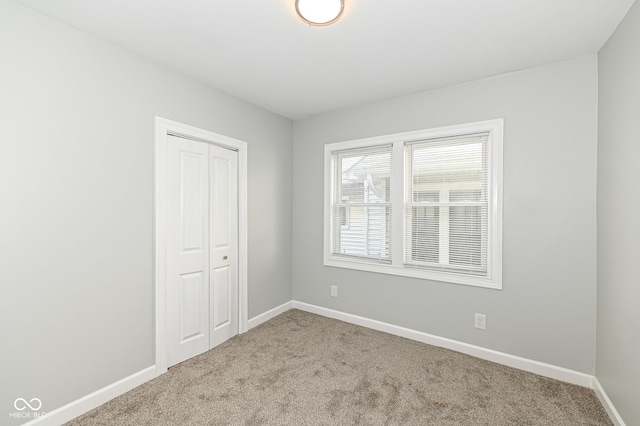 unfurnished bedroom with carpet flooring, baseboards, and a closet