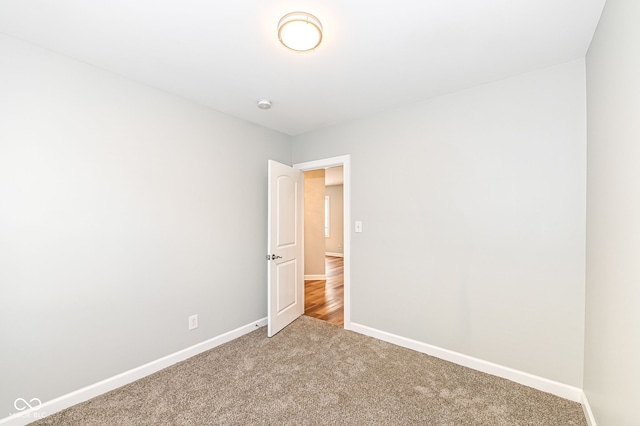 carpeted empty room featuring baseboards