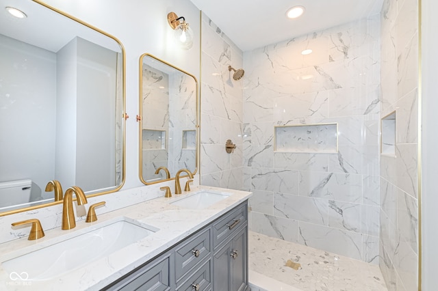 bathroom with a sink, tiled shower, toilet, and double vanity