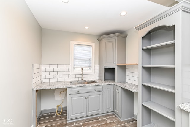 kitchen featuring backsplash, wood tiled floor, recessed lighting, gray cabinets, and a sink