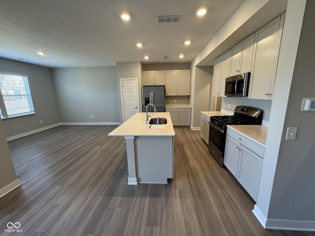 kitchen with dark wood finished floors, visible vents, appliances with stainless steel finishes, a sink, and baseboards