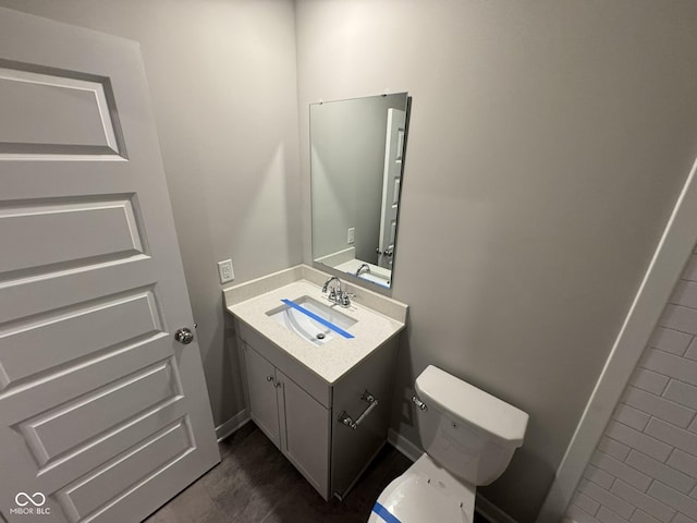 half bath with toilet, vanity, and baseboards