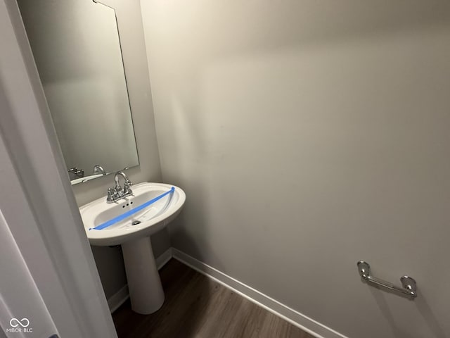 bathroom with a sink, baseboards, and wood finished floors