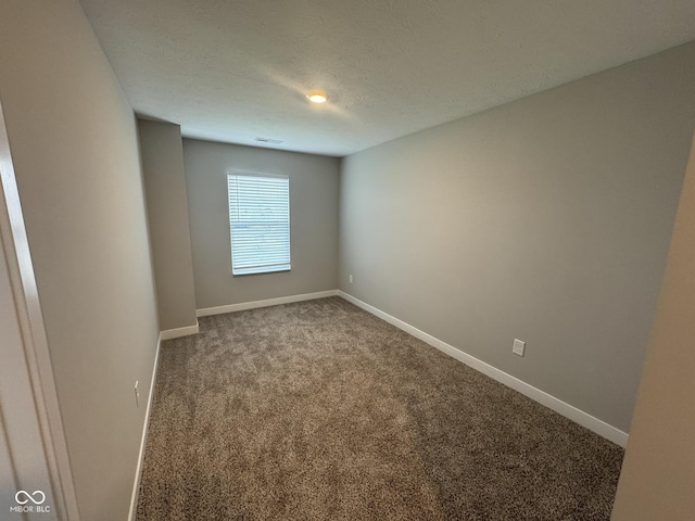 carpeted spare room featuring visible vents, baseboards, and a textured ceiling