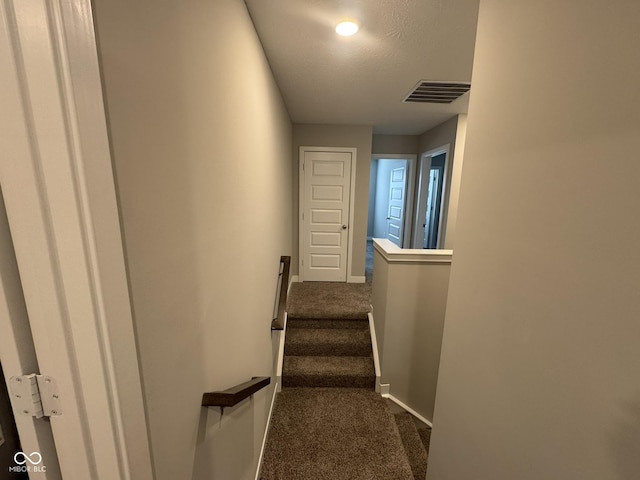 stairs with carpet, visible vents, and baseboards