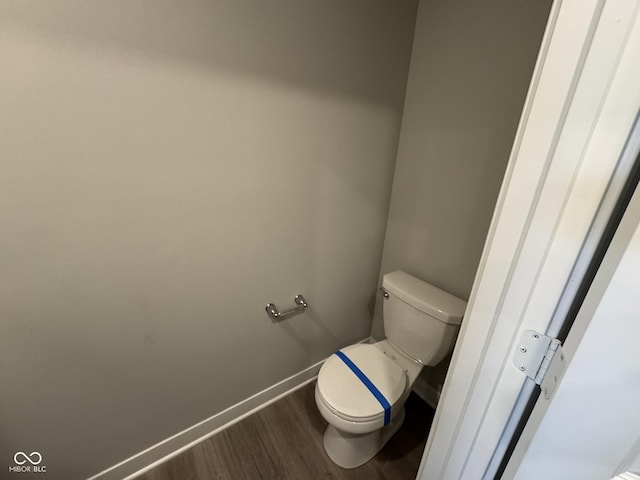 bathroom with toilet, baseboards, and wood finished floors