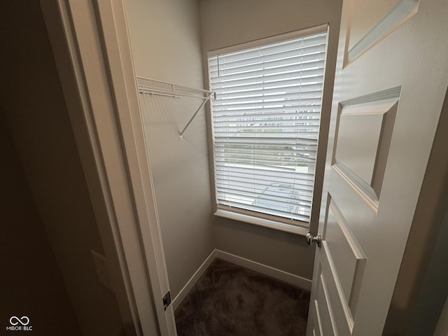 laundry area featuring baseboards and dark colored carpet