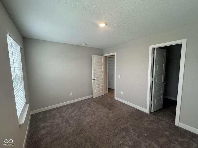 unfurnished bedroom with carpet floors, baseboards, and a walk in closet