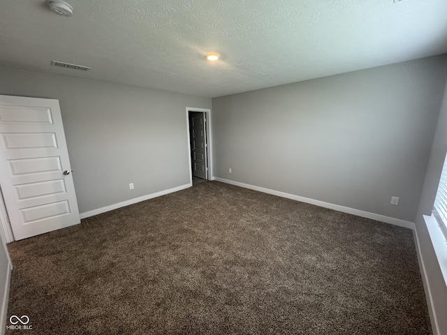 carpeted spare room featuring a textured ceiling, visible vents, and baseboards