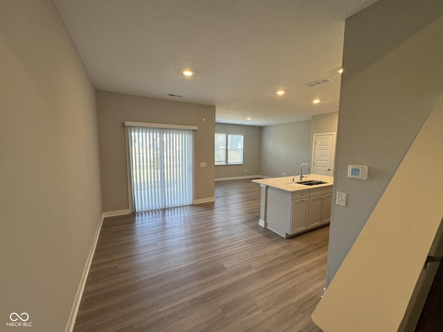 kitchen with visible vents, open floor plan, a sink, wood finished floors, and baseboards