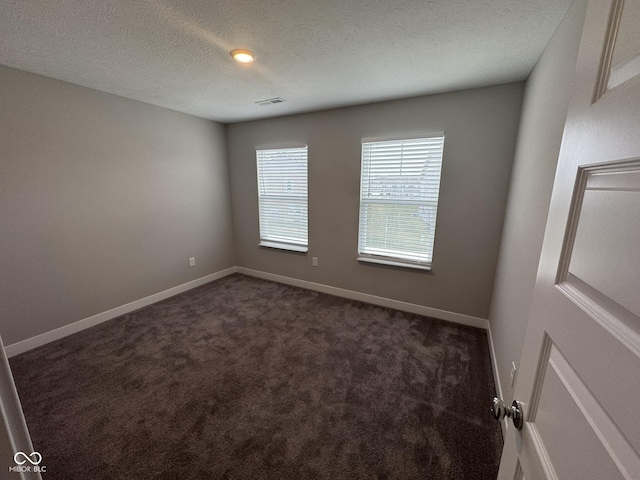 empty room with a textured ceiling, carpet floors, visible vents, and baseboards