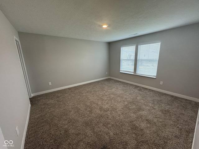 unfurnished room featuring carpet floors, baseboards, visible vents, and a textured ceiling