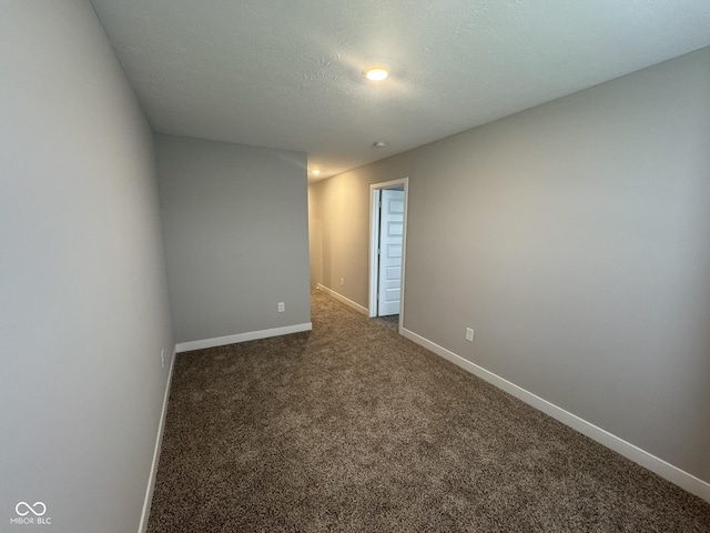 unfurnished room with dark carpet, a textured ceiling, and baseboards