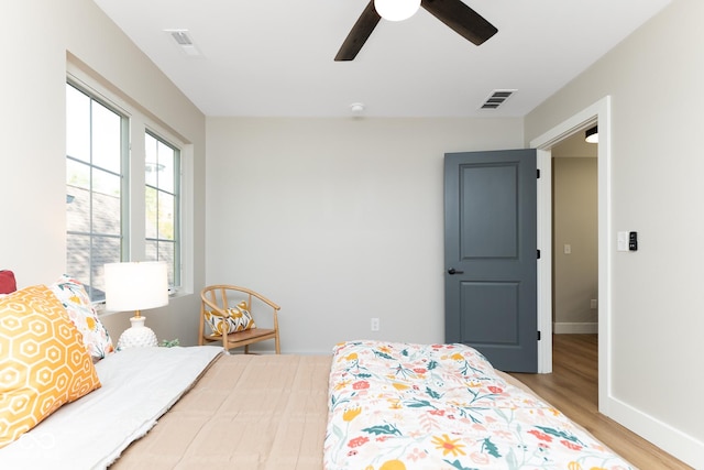 bedroom featuring a ceiling fan, baseboards, visible vents, and wood finished floors