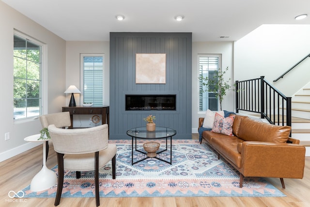 living area with a large fireplace, wood finished floors, visible vents, baseboards, and stairway