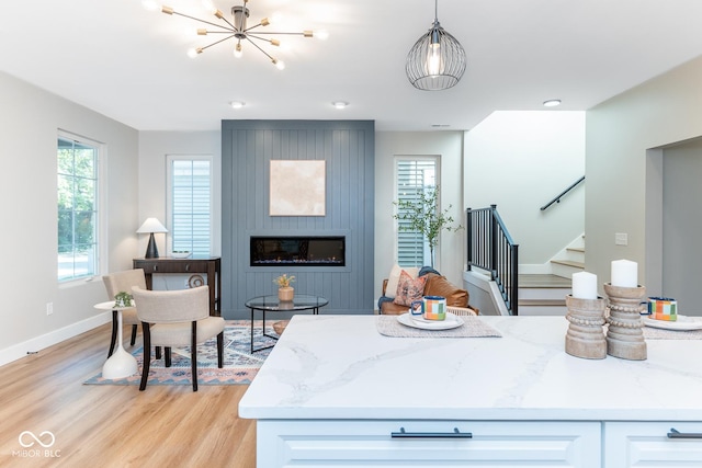 kitchen with light wood-type flooring, a fireplace, light stone countertops, and a healthy amount of sunlight