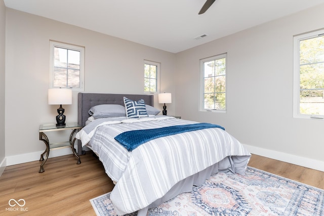 bedroom with light wood-type flooring, baseboards, visible vents, and a ceiling fan