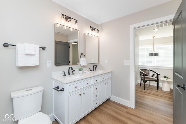 bathroom with baseboards, a sink, toilet, and wood finished floors