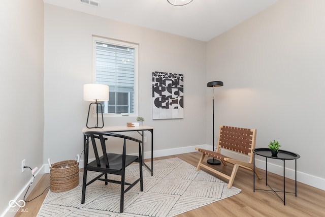 office space featuring wood finished floors, visible vents, and baseboards