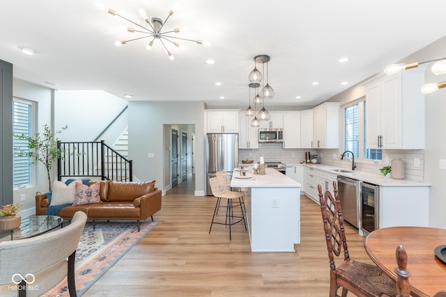 kitchen with appliances with stainless steel finishes, a kitchen bar, a sink, and white cabinetry