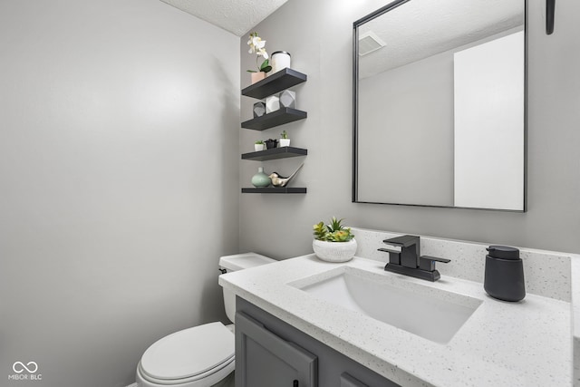 bathroom featuring toilet, visible vents, a textured ceiling, and vanity