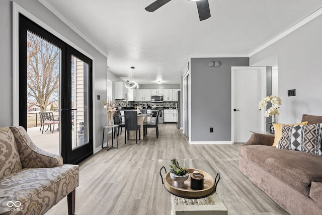 living room featuring light wood-style floors, baseboards, ornamental molding, and french doors