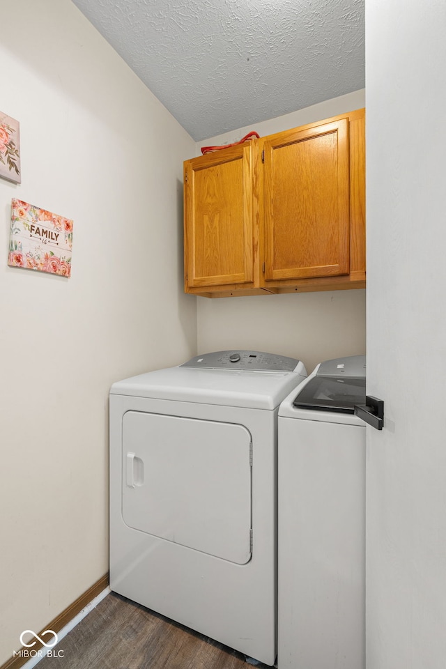 laundry room with washer and clothes dryer, cabinet space, a textured ceiling, wood finished floors, and baseboards