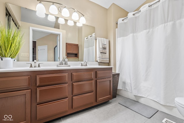 bathroom featuring a sink, double vanity, tile patterned flooring, and toilet