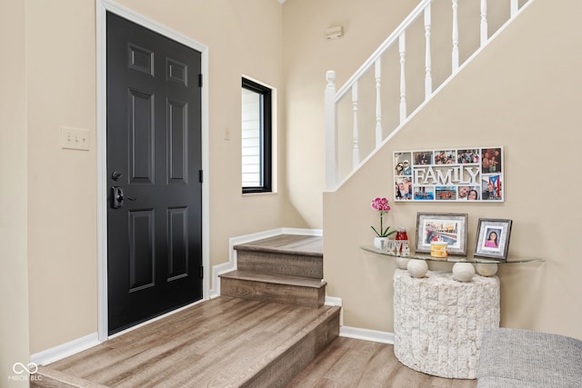 entrance foyer featuring wood finished floors, baseboards, and stairs