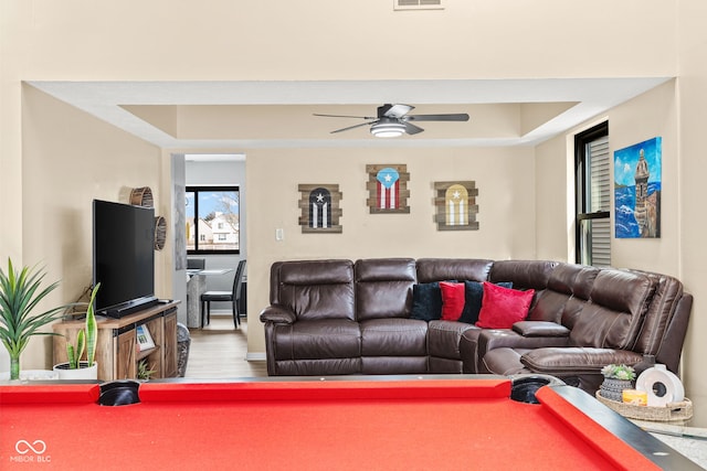 living room with wood finished floors, visible vents, billiards, a ceiling fan, and a raised ceiling