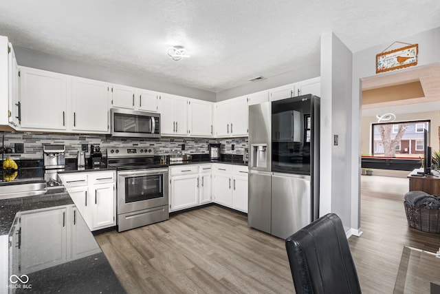 kitchen with white cabinetry, tasteful backsplash, appliances with stainless steel finishes, and wood finished floors