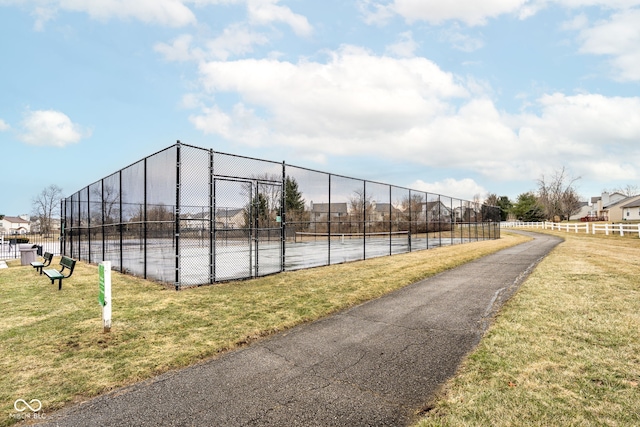 exterior space featuring a tennis court, a yard, fence, and a gate