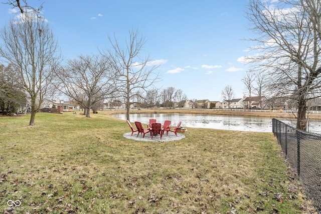 view of yard with an outdoor fire pit, a water view, and fence