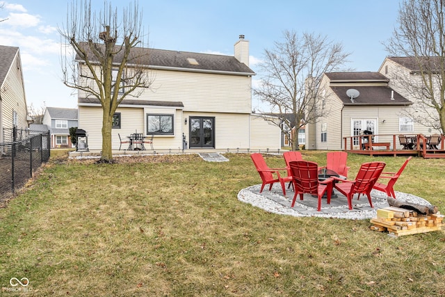 back of property with french doors, a lawn, a patio area, a fenced backyard, and a fire pit