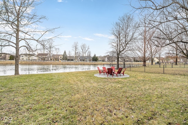 view of yard featuring an outdoor fire pit, a water view, and fence