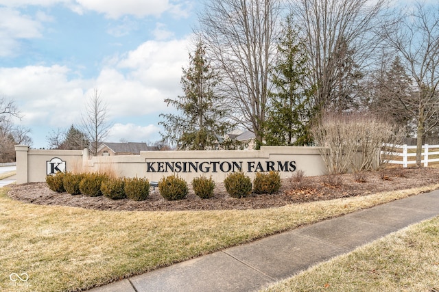 community / neighborhood sign featuring a lawn and fence