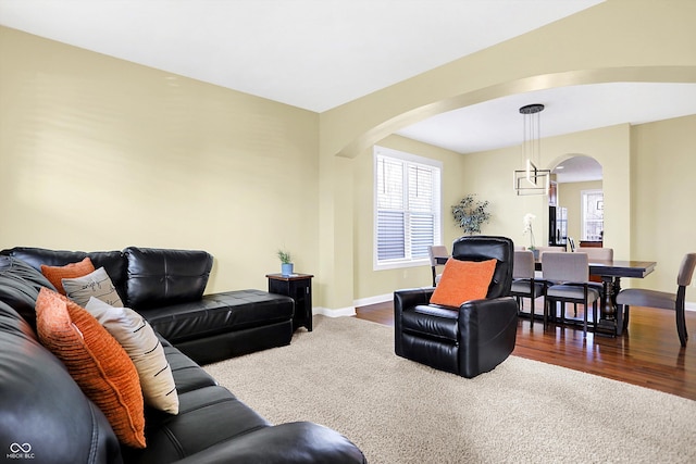 living room with baseboards, arched walkways, and wood finished floors