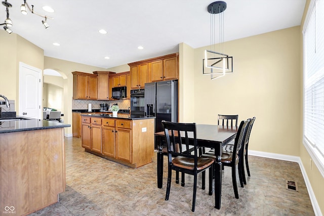 kitchen with black microwave, arched walkways, visible vents, fridge with ice dispenser, and decorative backsplash