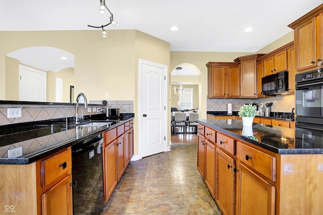 kitchen with backsplash, brown cabinetry, a sink, a peninsula, and black appliances